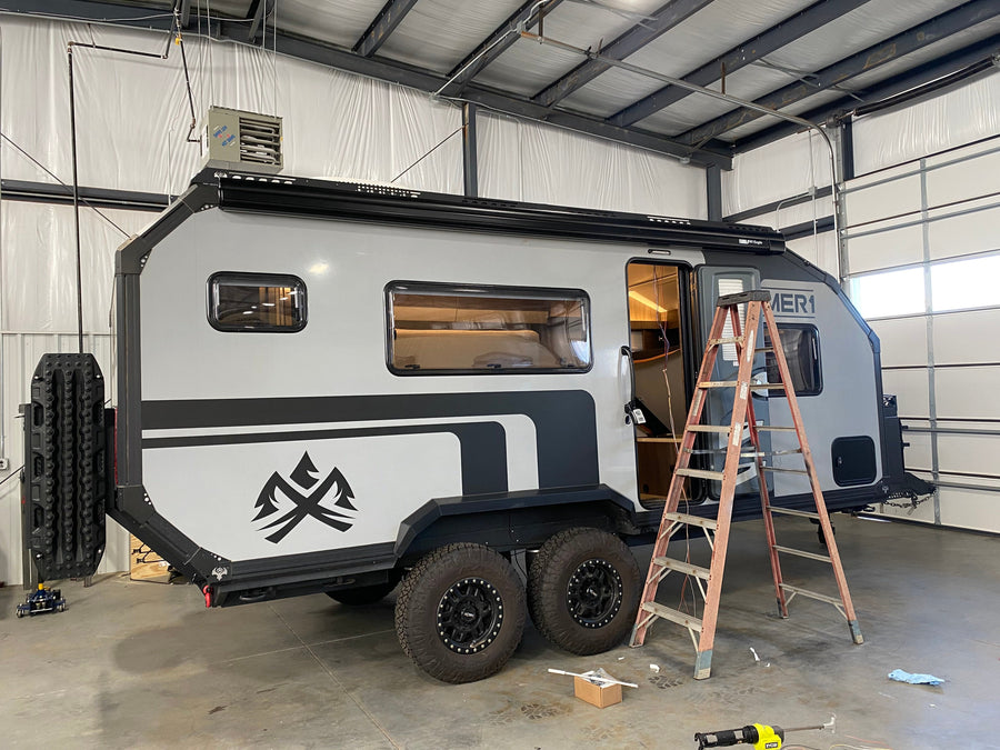 Compact dual-axle expedition trailer positioned inside the OAS workshop for upgrade work