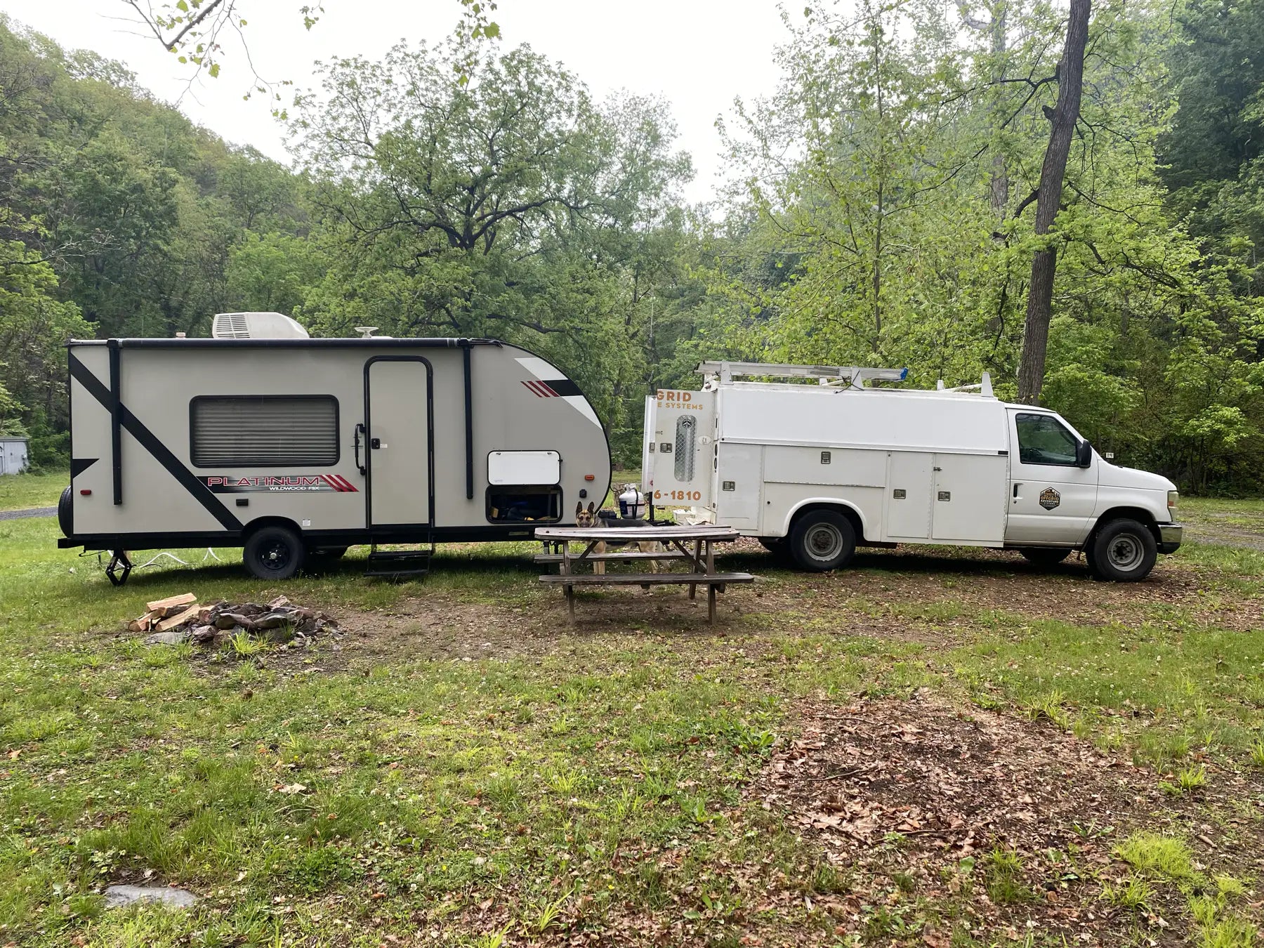 OAS service truck and travel trailer at a wooded campsite